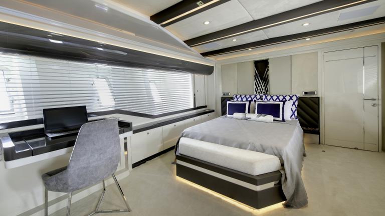 Large bedroom with comfortable bed, a wardrobe and a desk on the luxury yacht.